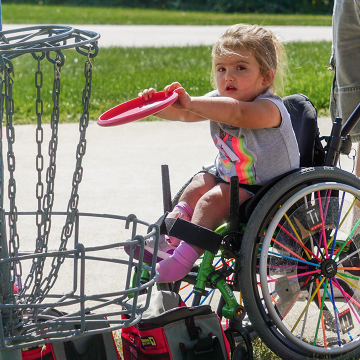 Little girl in wheelchair playing disc golf