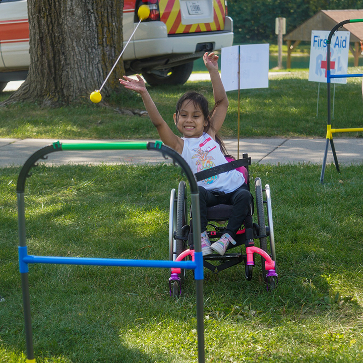 Little girl in wheelchair playing ladder ball yard game