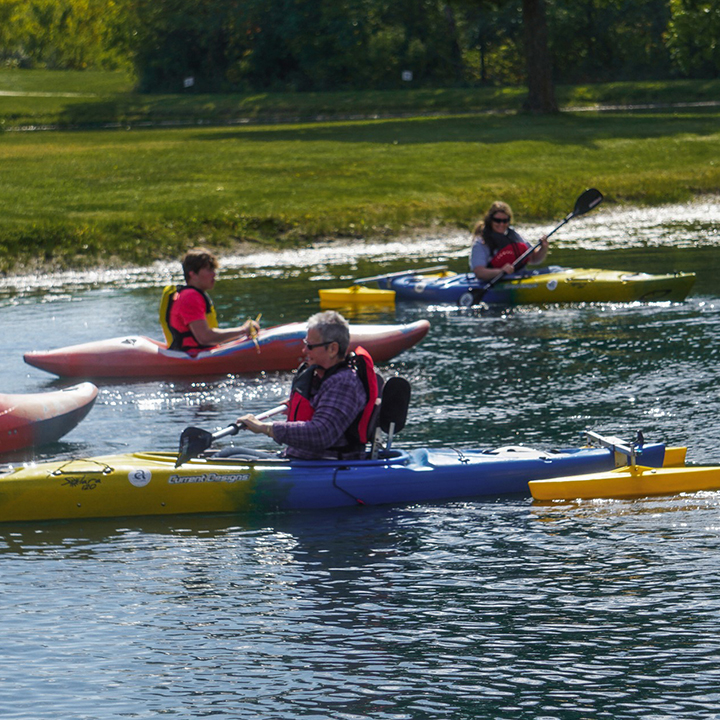 Man and woman using adapted kayaks in small lake