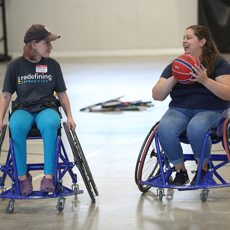 Two women in wheelchairs playing basketball